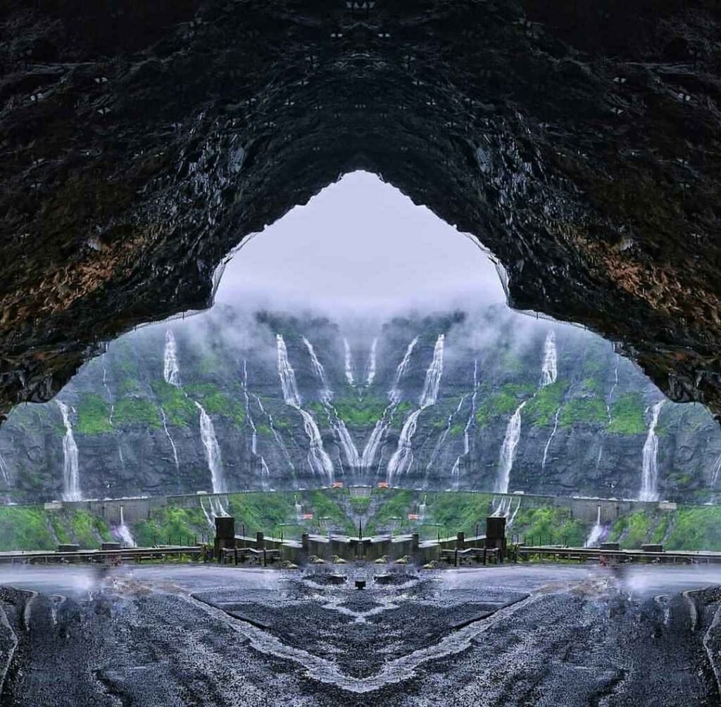 Malshej Ghat waterfalls viewed from a mountain tunnel during monsoon season, with misty clouds, lush green hills, and flowing streams in Maharashtra, India.