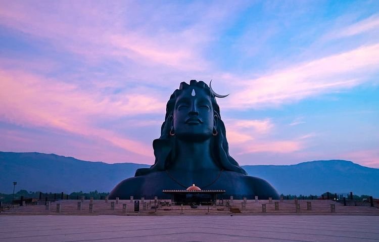 Adiyogi Shiva statue at Isha Yoga Center, Coimbatore, Tamil Nadu, with a beautiful pink and blue sunset sky in the background.