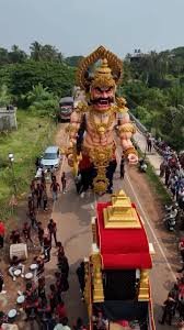 A large effigy of the demon Narakasura being paraded through the streets in Goa during Diwali celebrations, with people gathered around and drummers leading the procession